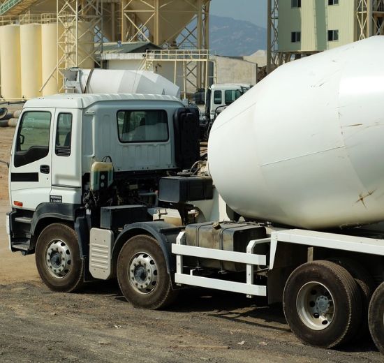doggett concrete construction A white cement mixer truck is parked at a construction site with industrial buildings and equipment in the background.